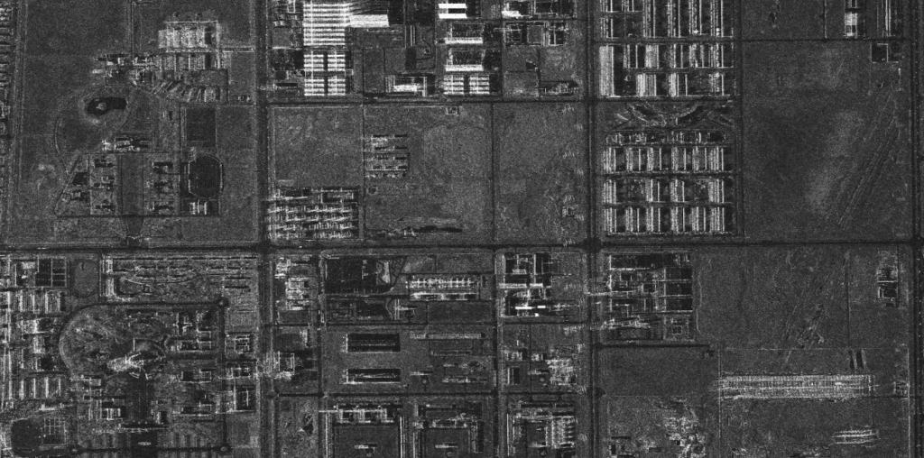 High-resolution SAR satellite image of an industrial area with buildings and roads visible through any weather